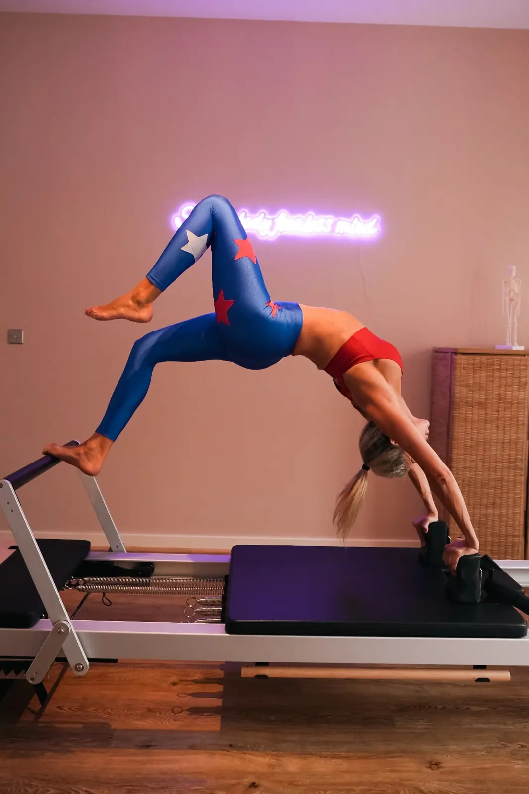 Reformer pilates backbend in a neon-lit studio