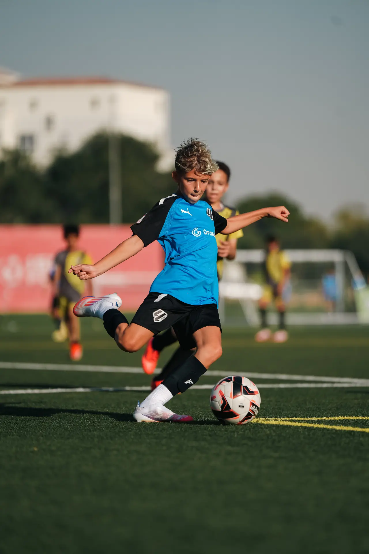 Youth striker winding up a shot — Dubai academy